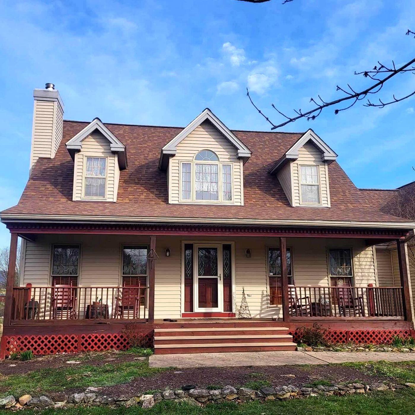 Cape Cod home with dormers, a new brown shingle roof and a full front porch