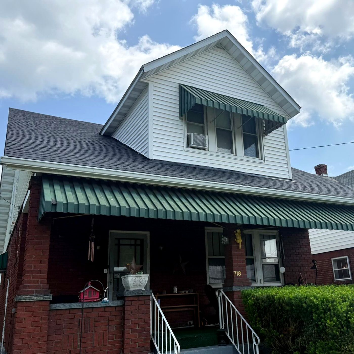 Two-story home with a new roof over the dormer and porch awning
