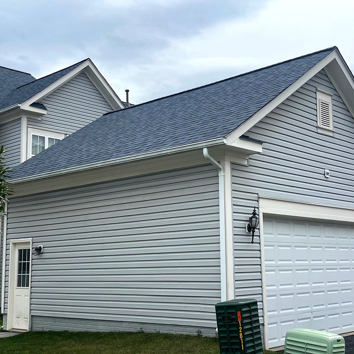 Two-story home with gray siding and a new roof over the garage