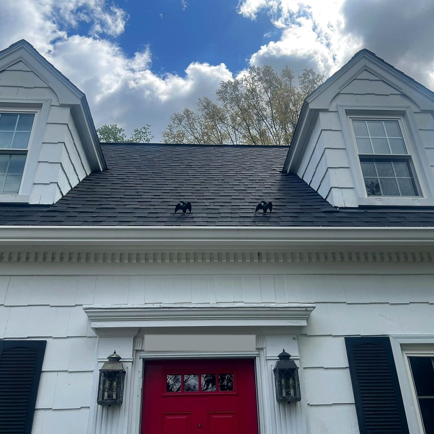White home with twin dormers and a new black roof