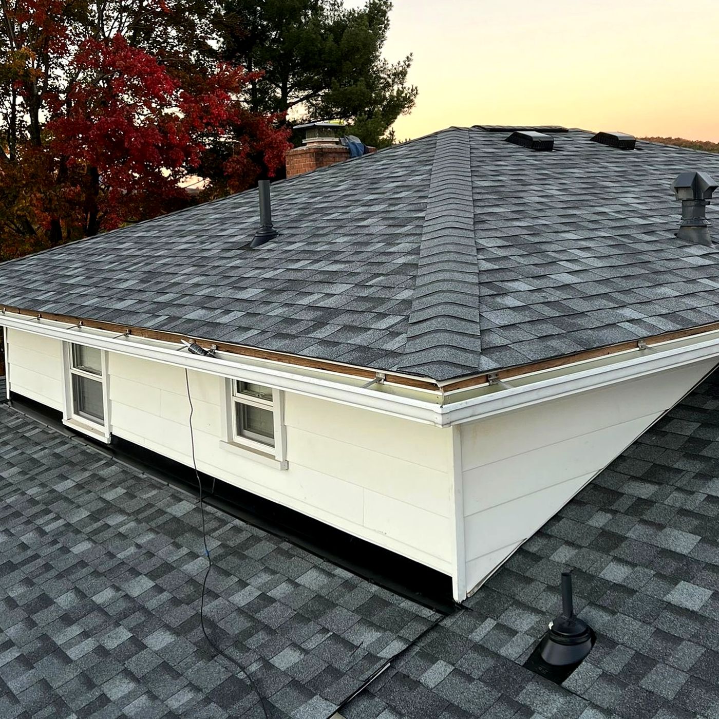 New hip roof on a white house at dusk