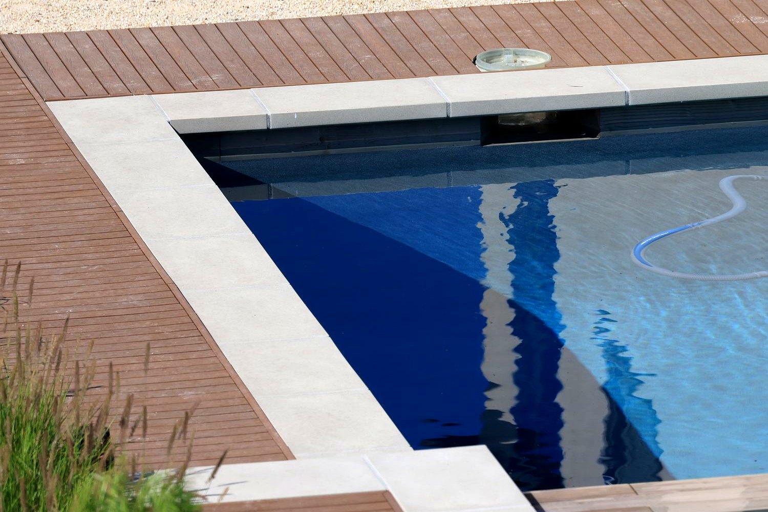 Brown capped composite deck boards wrapped around a backyard pool