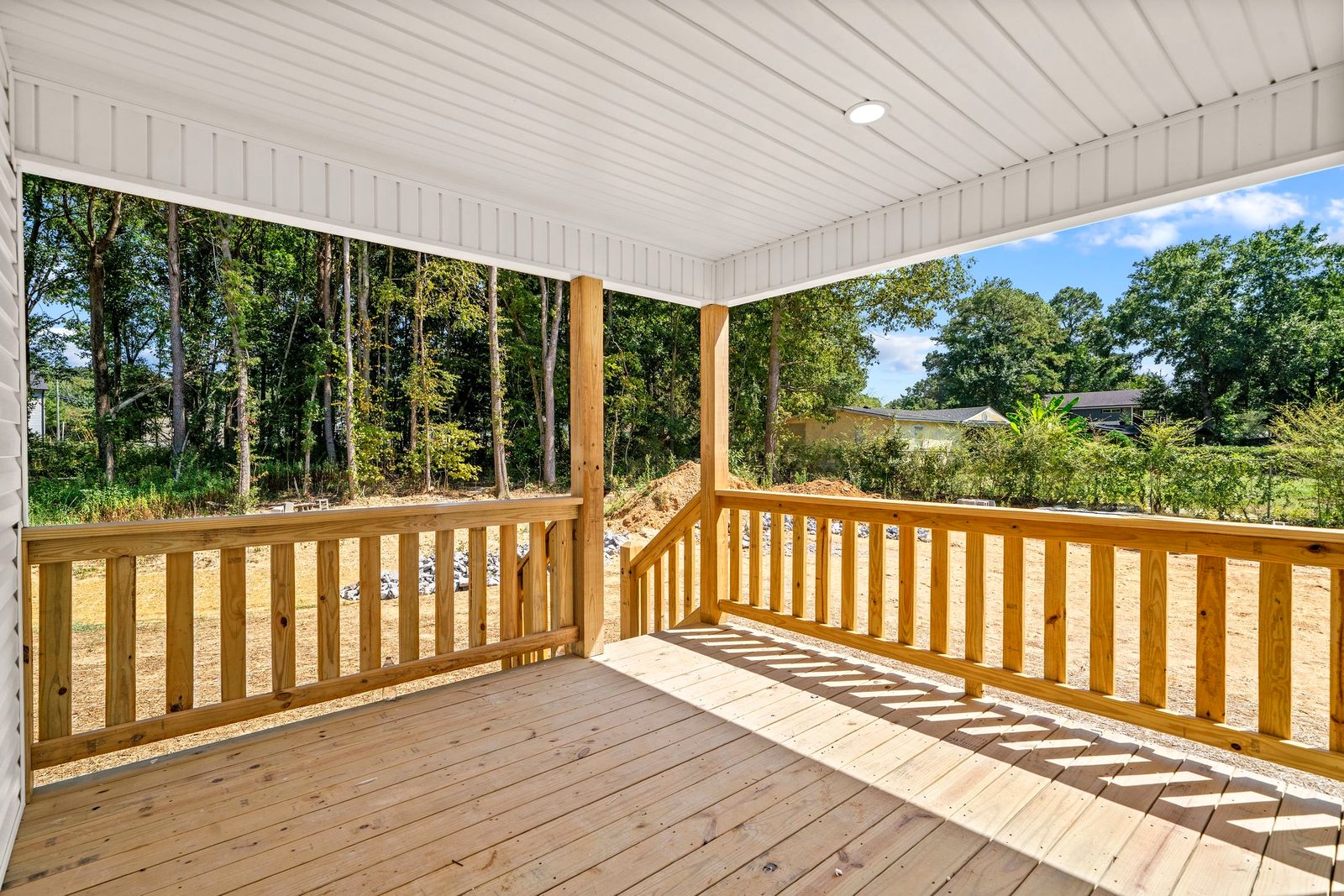 New pressure-treated wood deck with wood railings under a covered roof