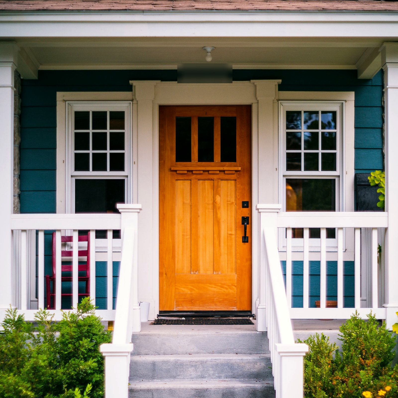 Craftsman wood entry door with glass lites on a white-railed front porch