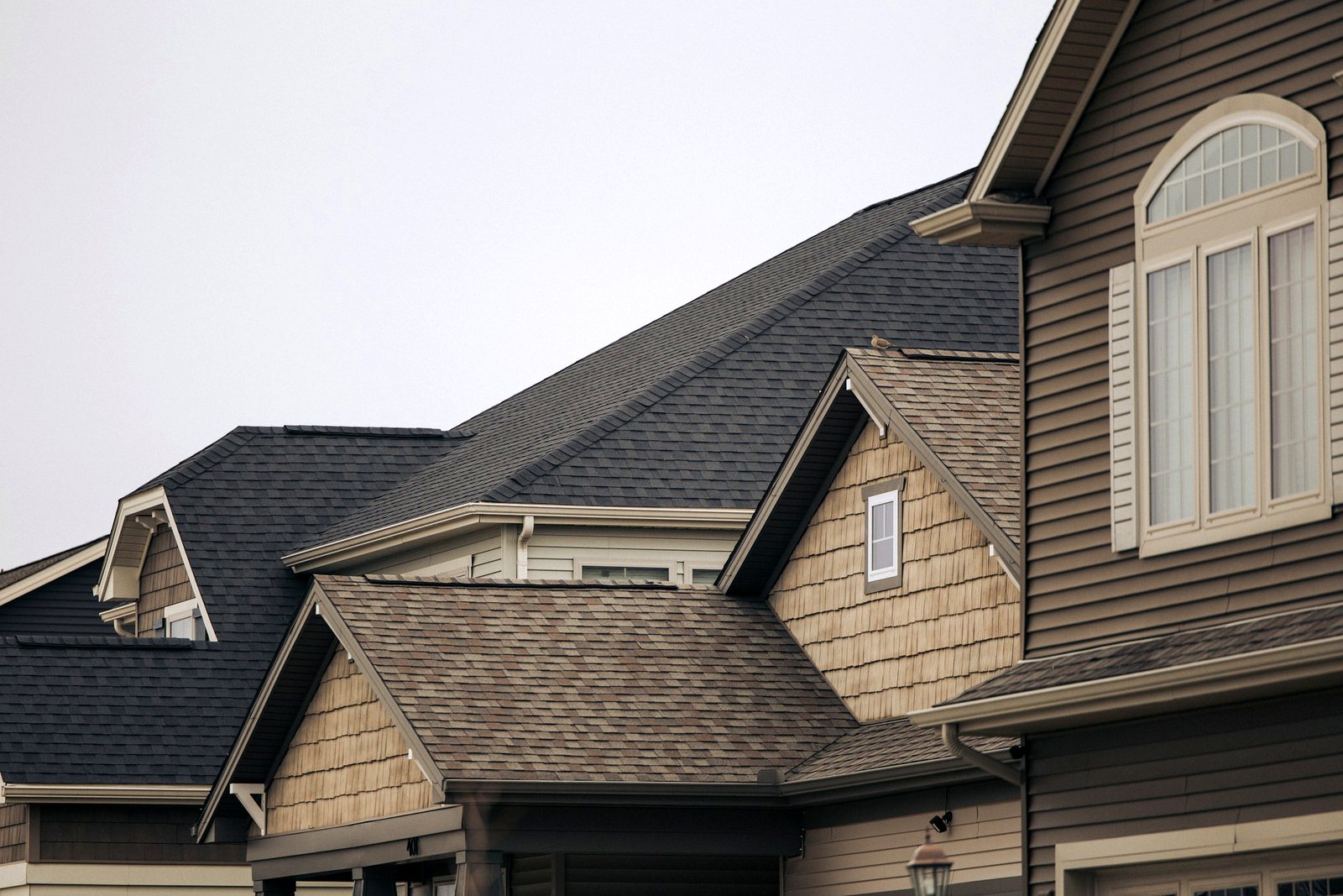 Architectural asphalt shingles on a two-story home with shake gables