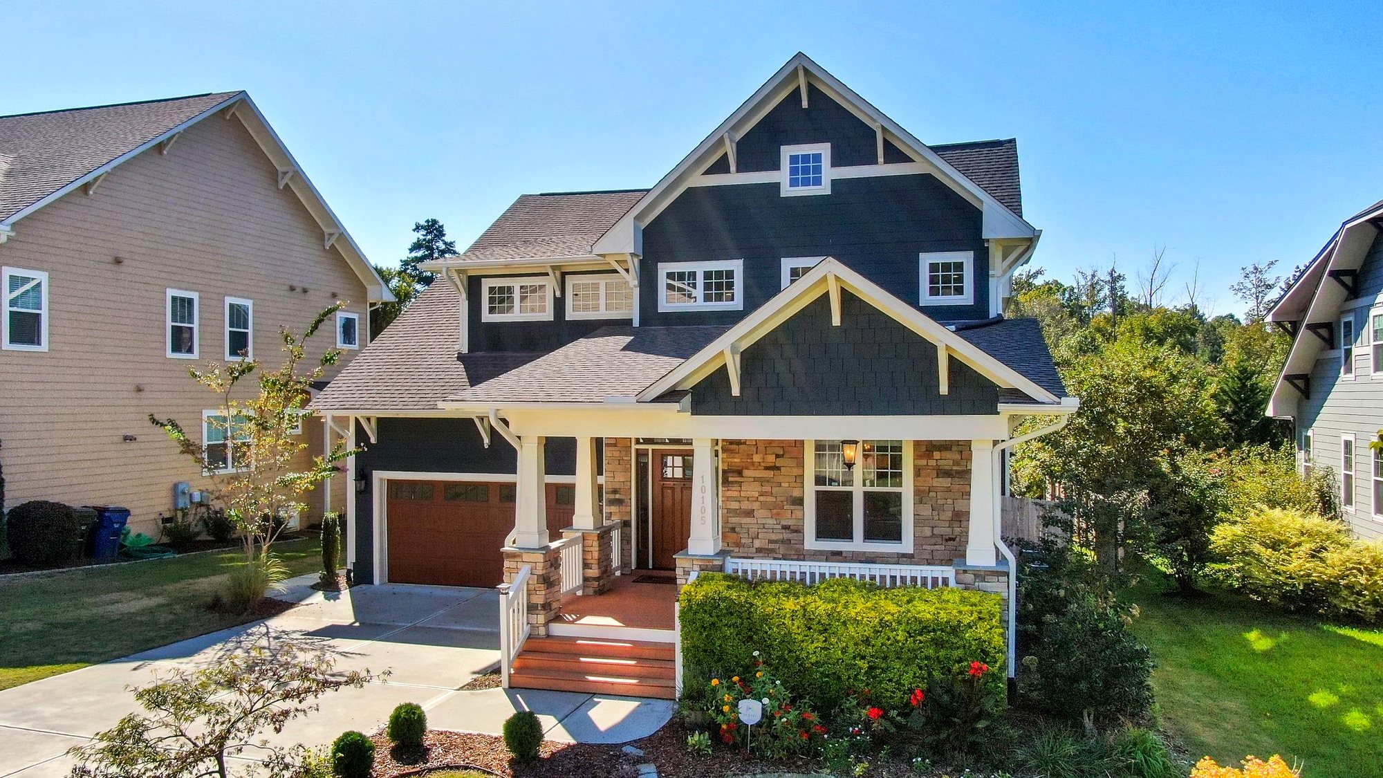 New navy craftsman home with lap siding, shake gables, stone and a covered porch